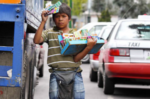 In this picture we see a boy selling chewing gum in the streets of Mexico City. Often children do not go to school in order to make money. As shown in this picture children are risking their lives by doing jobs like these. Apart from risking their lives they are not getting an education and missing school to do this work.